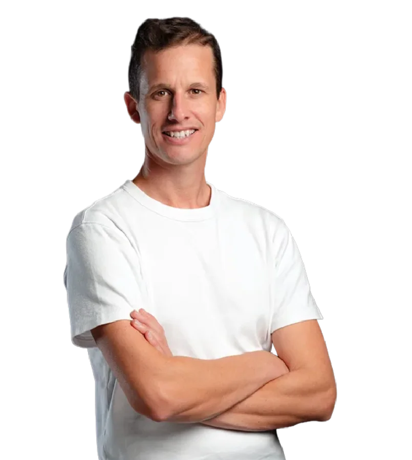 Souriant, William porte un tee-shirt blanc et se tient les bras croisés, dans un portrait en buste qui montre son visage.